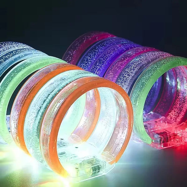 A close-up shot of ten glowing LED flash bracelets in various colors, including green, orange, and purple.