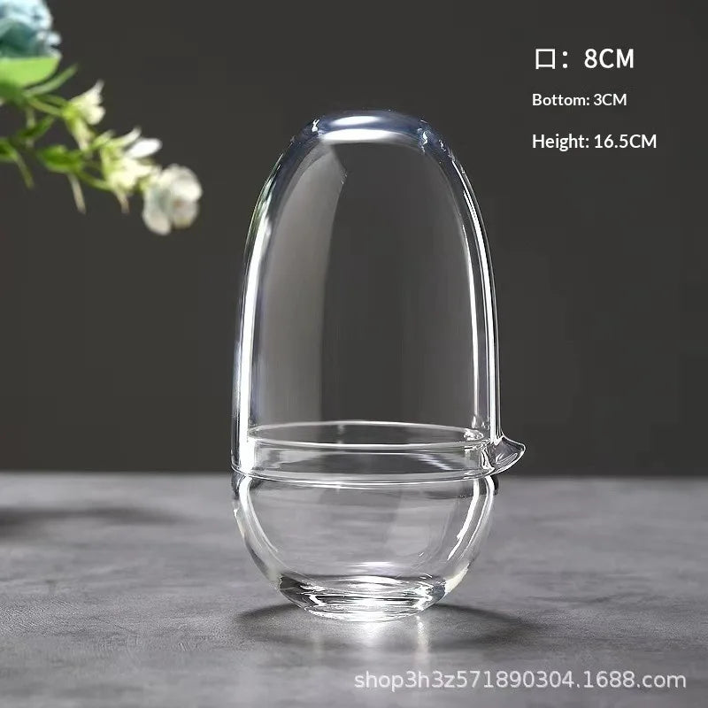 A clear glass vase with a rounded shape is shown on a dark surface, measuring 8cm in diameter and 16.5cm in height.