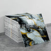 A sheet of faux marble wallpaper featuring abstract black, white, and gold veining displayed next to a stack of tiles.