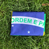A folded blue flag with green text reading ORDEM E PA displayed on green grass.
