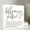 A white sign with black script that reads difference maker and a definition below it.