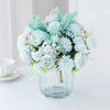 A bouquet of light blue and white artificial silk peony flowers arranged in a clear glass vase.