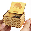 A hand holds an open carved wooden music box featuring a profile of a woman.