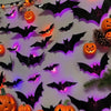 Exhibición de pared con siluetas de murciélago y araña negras iluminadas por luces LED moradas y naranjas.