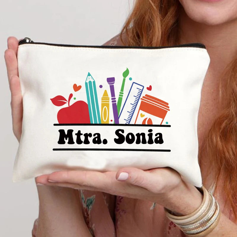 A cream-colored canvas makeup bag with a black design featuring pencils, rulers, and the name Mtra. Sonia.