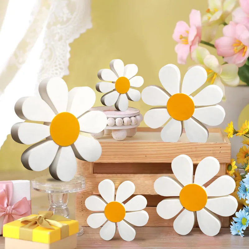 Set of three white and orange wooden daisy flower ornaments displayed on a light wood surface.