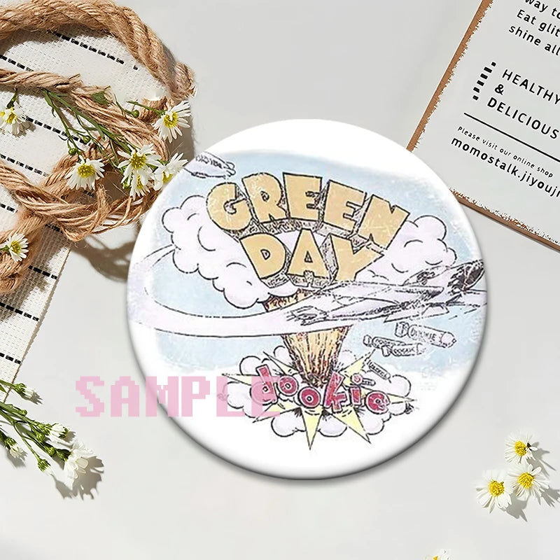 A round button pin featuring a distressed illustration of the words GREEN DAY with smoke and explosion effects.