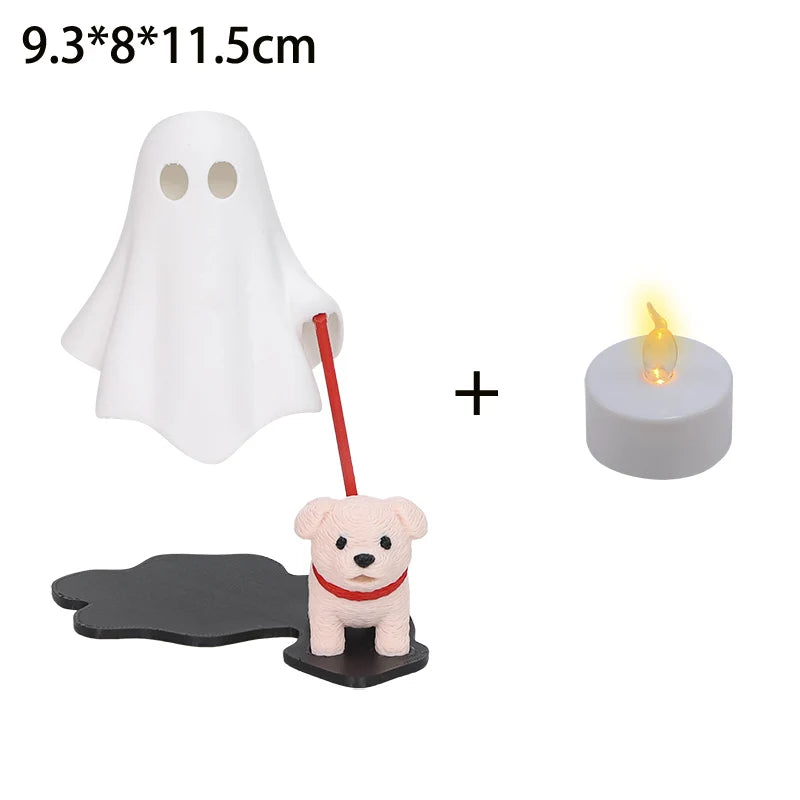 A white ghost figurine with a red rod and a small dog figure, next to a lit candle.
