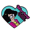A glossy enamel pin badge featuring a stylized illustration of a woman with dark hair and glasses against a teal background.