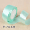 A roll of light mint green silk satin ribbon used for gift wrapping and craft projects.