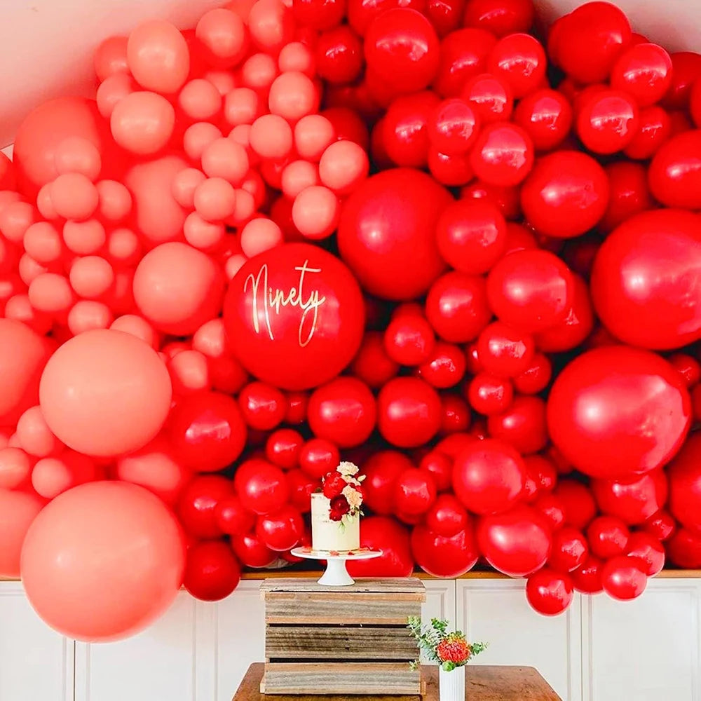 A close-up of a large arrangement of red and pink latex balloons for parties and celebrations.