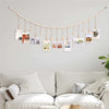 A string of wooden clothespins displaying various framed photos and cards on a light gray wall.