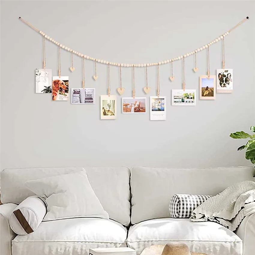 A string of wooden clothespins displaying various framed photos and cards on a light gray wall.