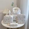 A set of white backpacks and accessories featuring a red bow print on a light-colored surface.
