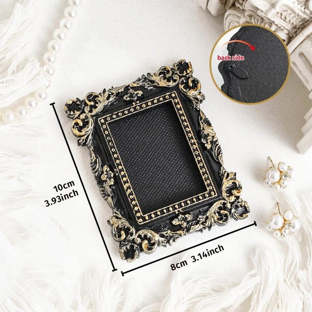 A black vintage baroque resin hanging photo frame with gold accents displayed on a white fluffy surface.