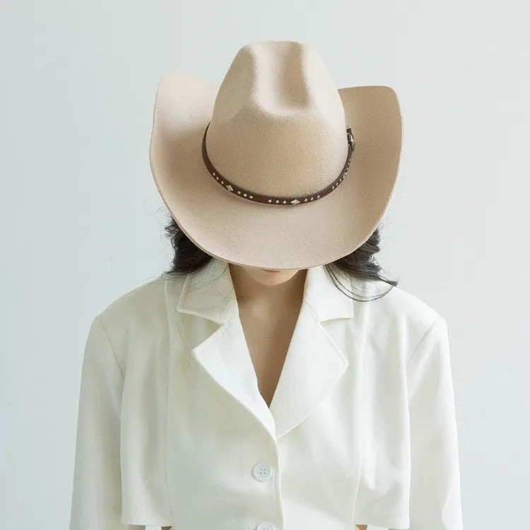 A woman wearing a beige wool cowboy hat with a studded leather band and a white collared shirt.