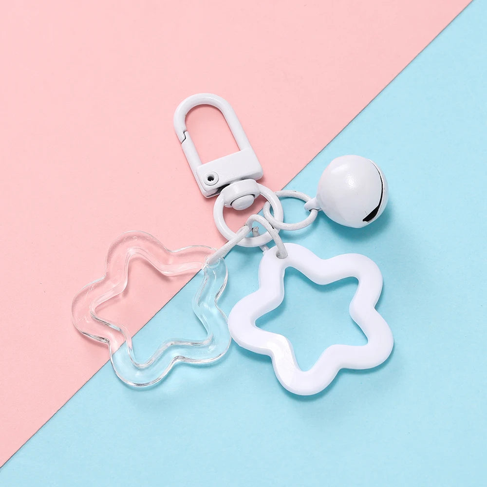 A white star charm pendant keychain with a silver clasp and a white spherical bead on a pink and blue background.