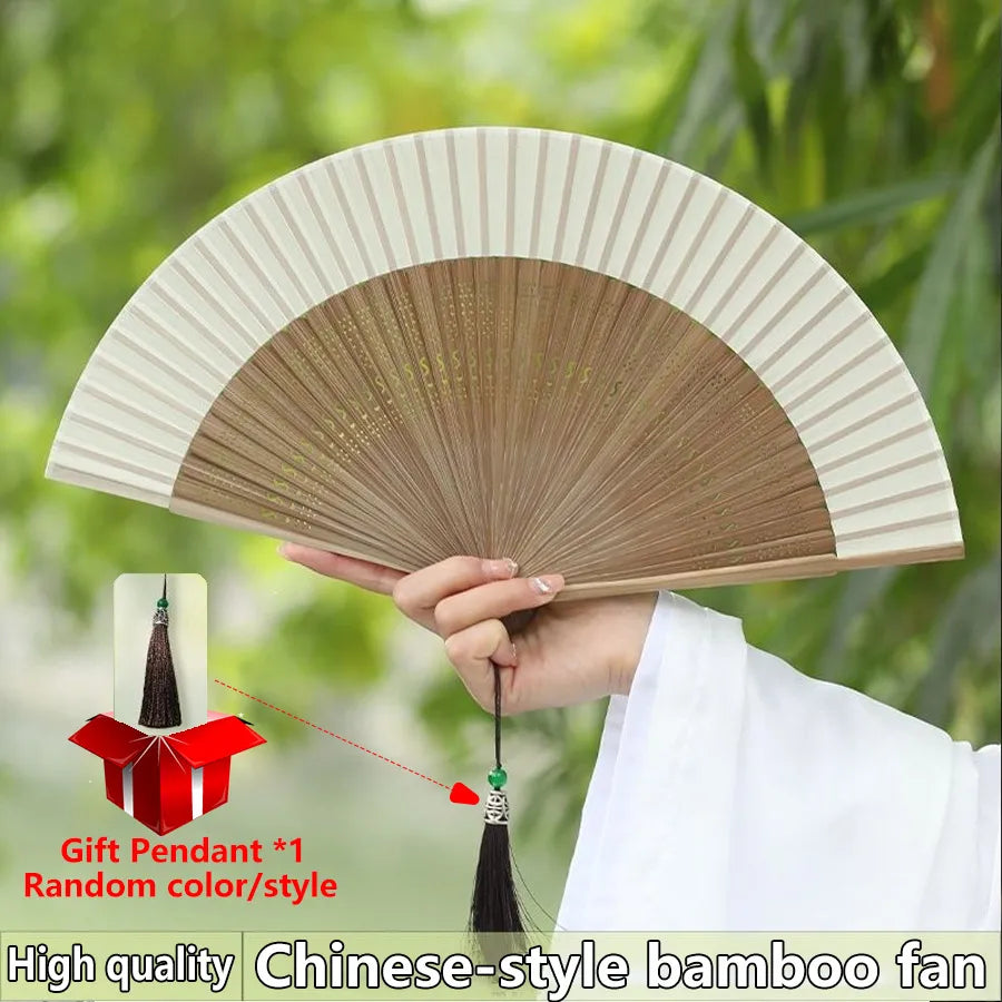 A hand holds a high quality Chinese-style bamboo fan with decorative pendant, showing its pleated surface.