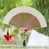 A hand holds a high quality Chinese-style bamboo folding fan with a decorative pendant, showing its pleated surface.