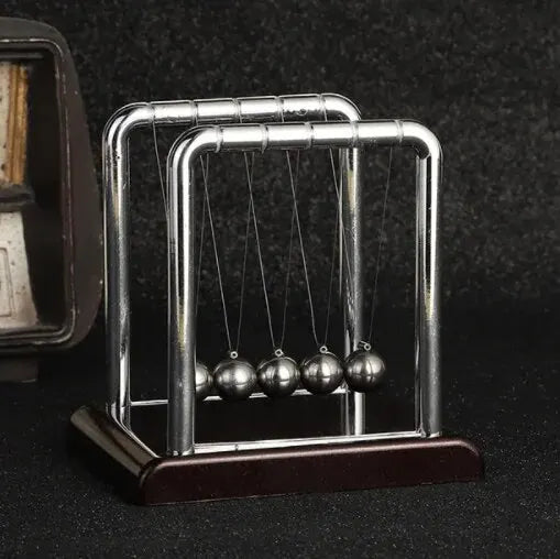 A silver Newton's cradle with balance balls on a dark wooden base.