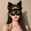A woman wearing an elegant black lace half-face mask with cat ears and long dark hair.