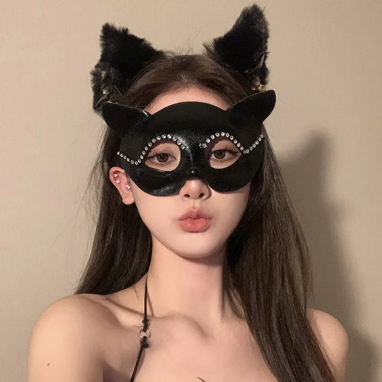 A woman wearing an elegant black lace half-face mask with cat ears and long dark hair.