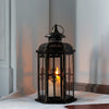 A vintage Nordic iron candle lantern with glass panes sitting on a white surface.