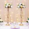 A gold-toned rose ball centerpiece with silk artificial flowers displayed on a white table.