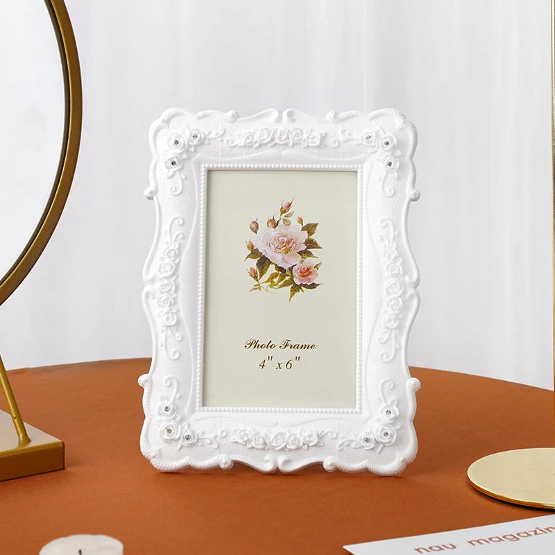 Elegant white photo frame with a distressed border and a floral design displayed on a brown surface.
