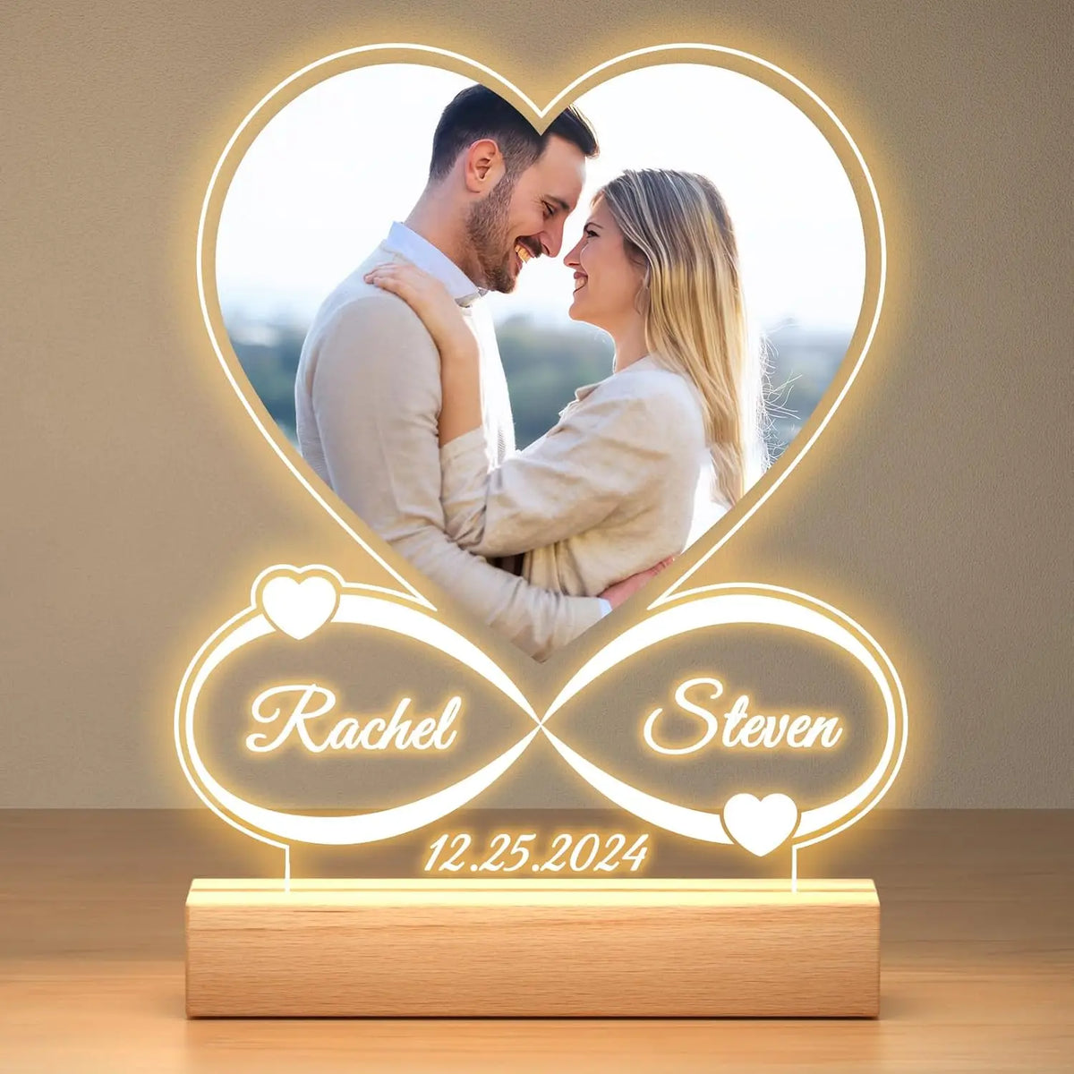 A glowing acrylic photo frame featuring a heart shape with names Rachel and Steven and a date 12.25.2024