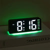 A black LED digital alarm clock with a bright green ambient glow displaying 8:16 and the day of the week.