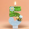 A birthday candle shaped like the number 5, decorated with a daisy and a bee, set against a soft orange background.