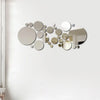 A collection of various sized, reflective circular mirror decals arranged in an organic, scattered pattern on a white wall.