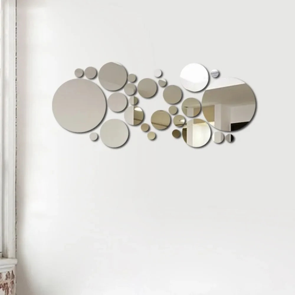 A collection of various sized, reflective circular mirror decals arranged in an organic, scattered pattern on a white wall.