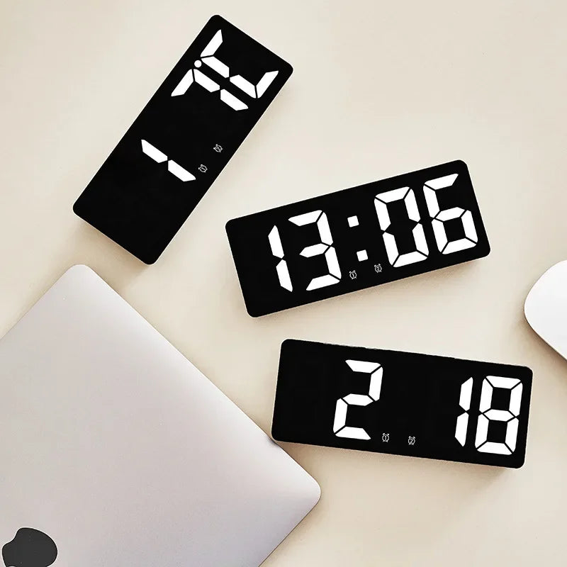 A black LED digital alarm clock displaying time, temperature, and other functions, resting on a white laptop.