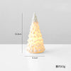 A small, white ceramic glow-in-the-dark Christmas tree decor shaped like a cone.