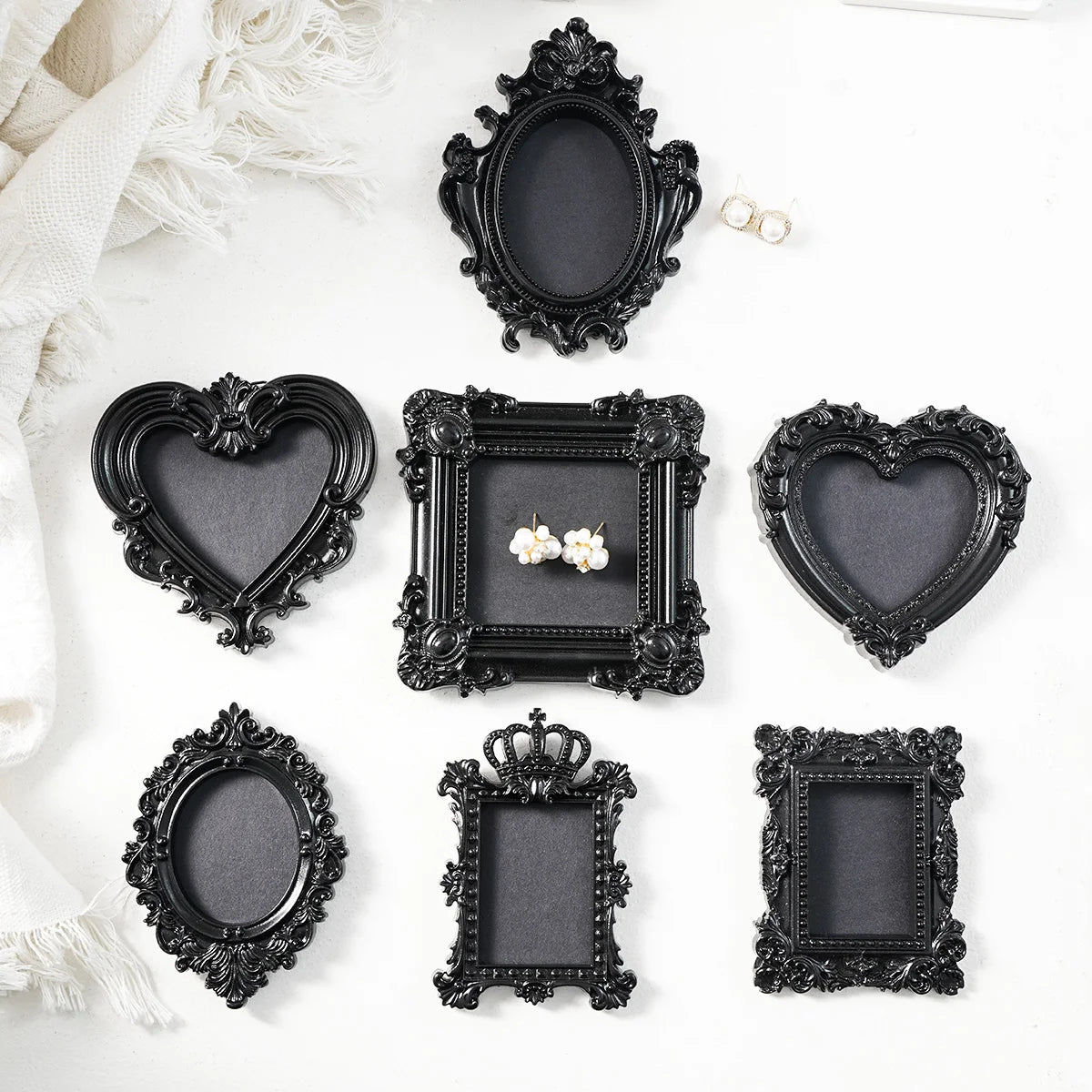 A collection of black ornate resin wall decor pendants and frames displayed on a white surface.