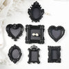 A collection of black ornate resin wall decor pendants and frames displayed on a white surface.