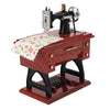A vintage sewing machine music box with a silver crank and decorative wooden base.