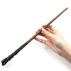 A hand holds a dark brown, twisted metal magic wand against a white background.