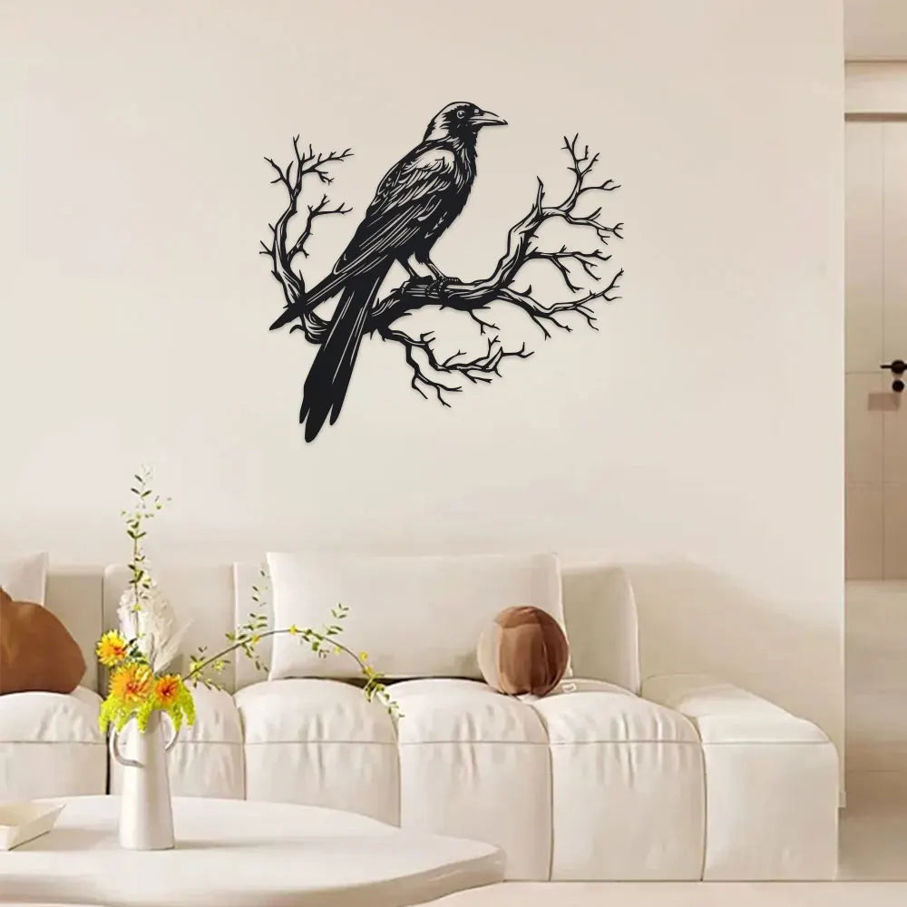 Black raven silhouette on a bare tree branch metal wall art displayed above a white sofa.