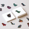 Collection de stickers graffiti colorés de dinosaures et d'animaux éparpillés sur une surface blanche.