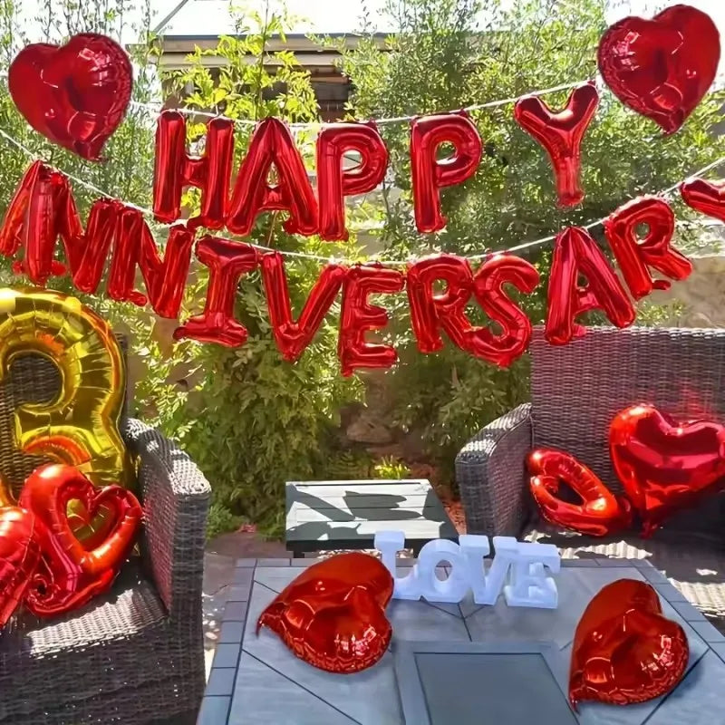 Red foil balloons spelling HAPPY ANNIVERSARY hanging outdoors among green foliage