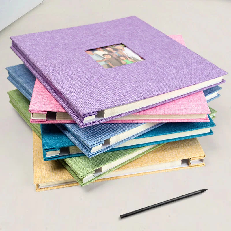 A stack of colorful linen front scrapbook memory books in shades of purple, pink, blue, and green.