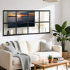 A modern black framed window mirror reflecting a sunset and interior decor in a living room setting.