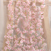 A long garland of pink artificial sakura flowers hangs against a sheer white background.