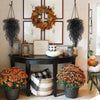 A decorative arrangement of silk morning glory vine hanging flowers in various shades of orange and green on a dark wooden ta