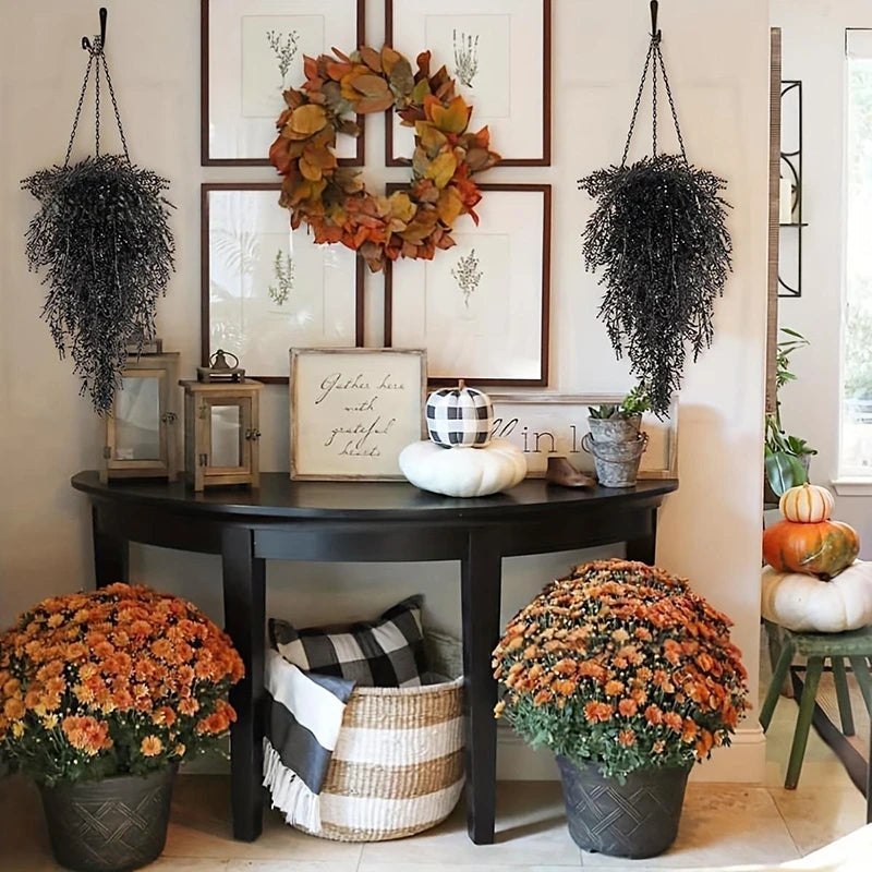 A decorative arrangement of silk morning glory vine hanging flowers in various shades of orange and green on a dark wooden ta