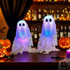 Two glowing white ghost decorations with blue light illuminating a wooden surface in a dimly lit shelf setting.