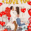 A set of red heart balloons and a blue bear decoration for a romantic theme.